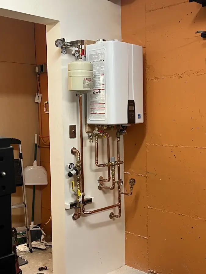 Plumbing technician inspecting water heater connections in Wilton
